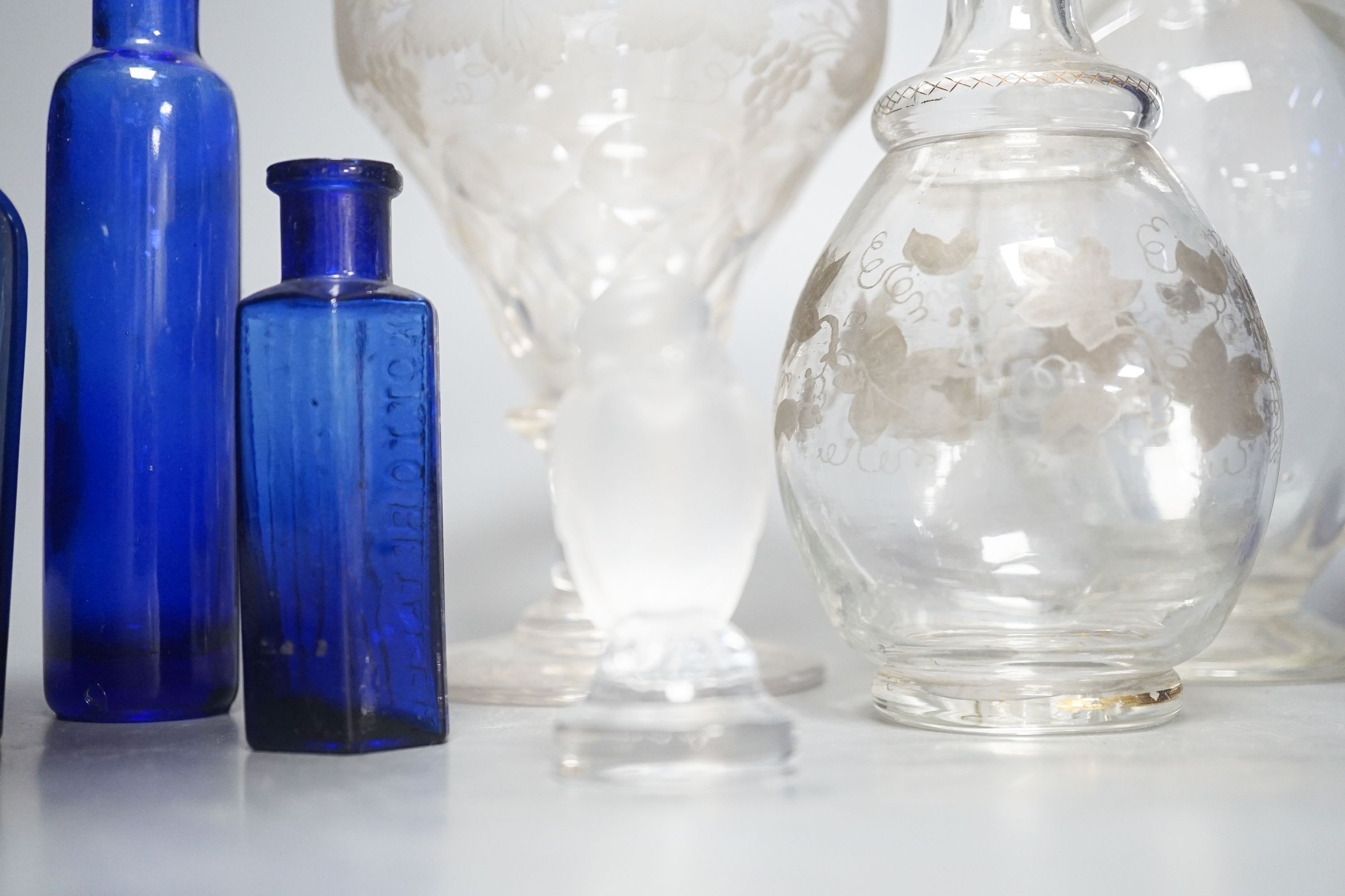 A Lalique frosted glass bird, etched Wedgwood ‘plant a tree ‘73’ glass, other etched glasses, decanters and blue glass pharmacy bottles